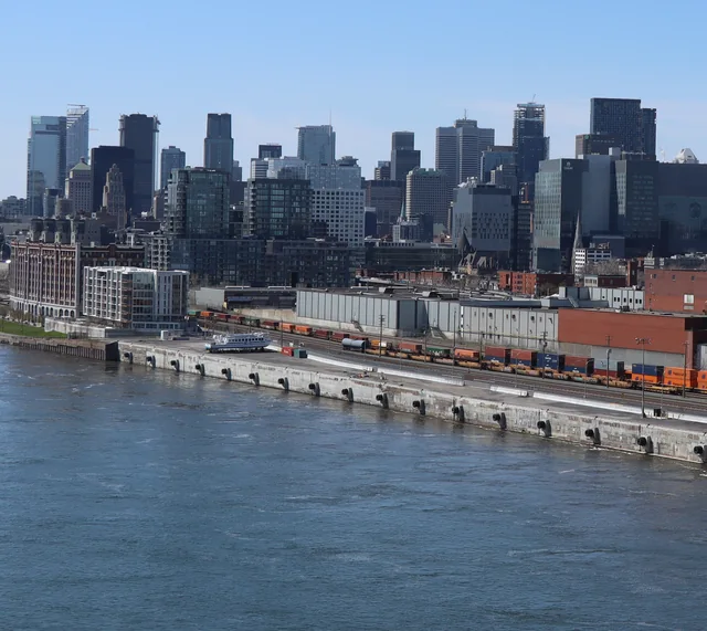 Port of Montreal wharf with container trains on the quay and the downtown skyline behind
